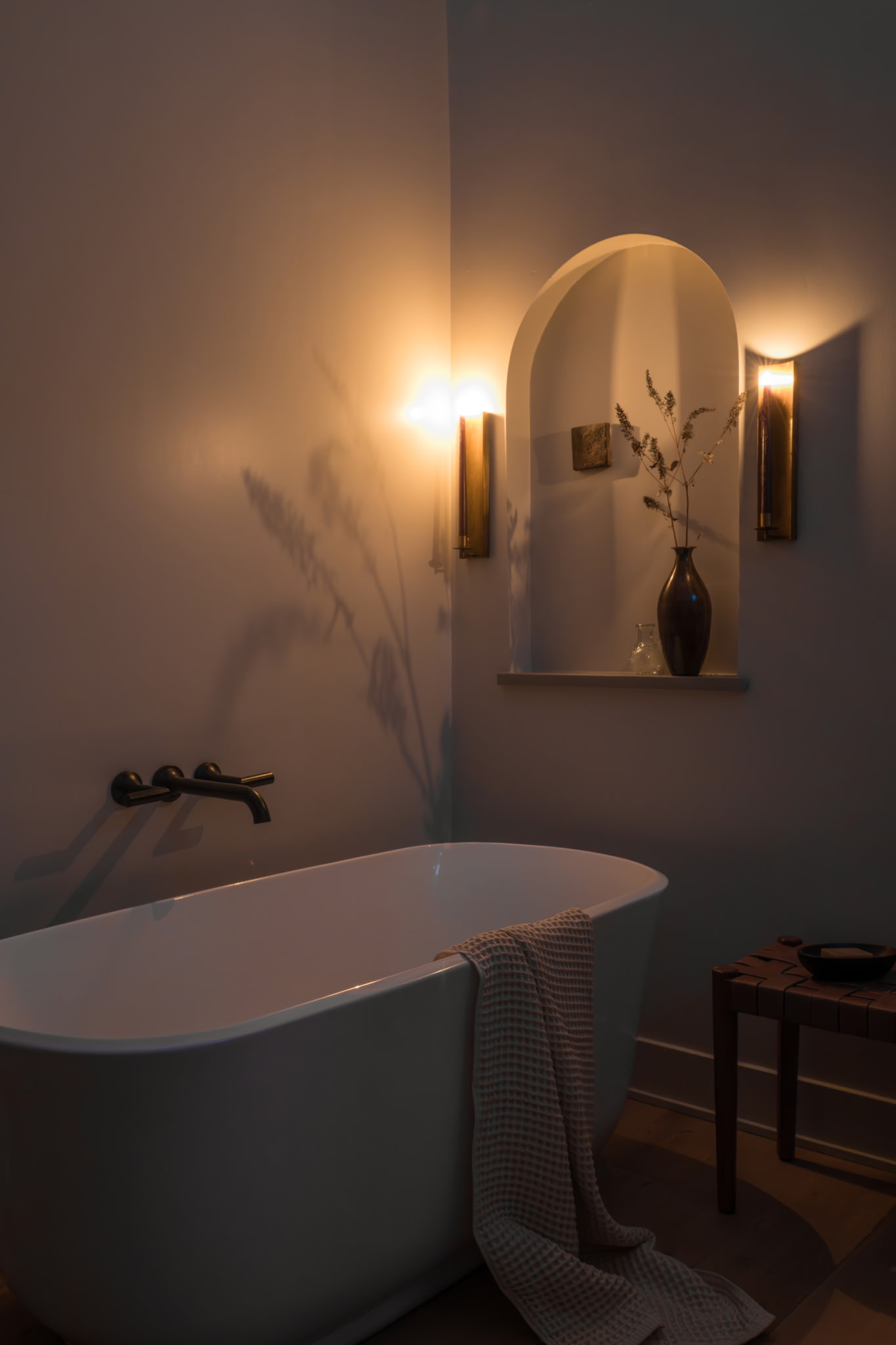 Warm candlelit bathroom corner with woven bench