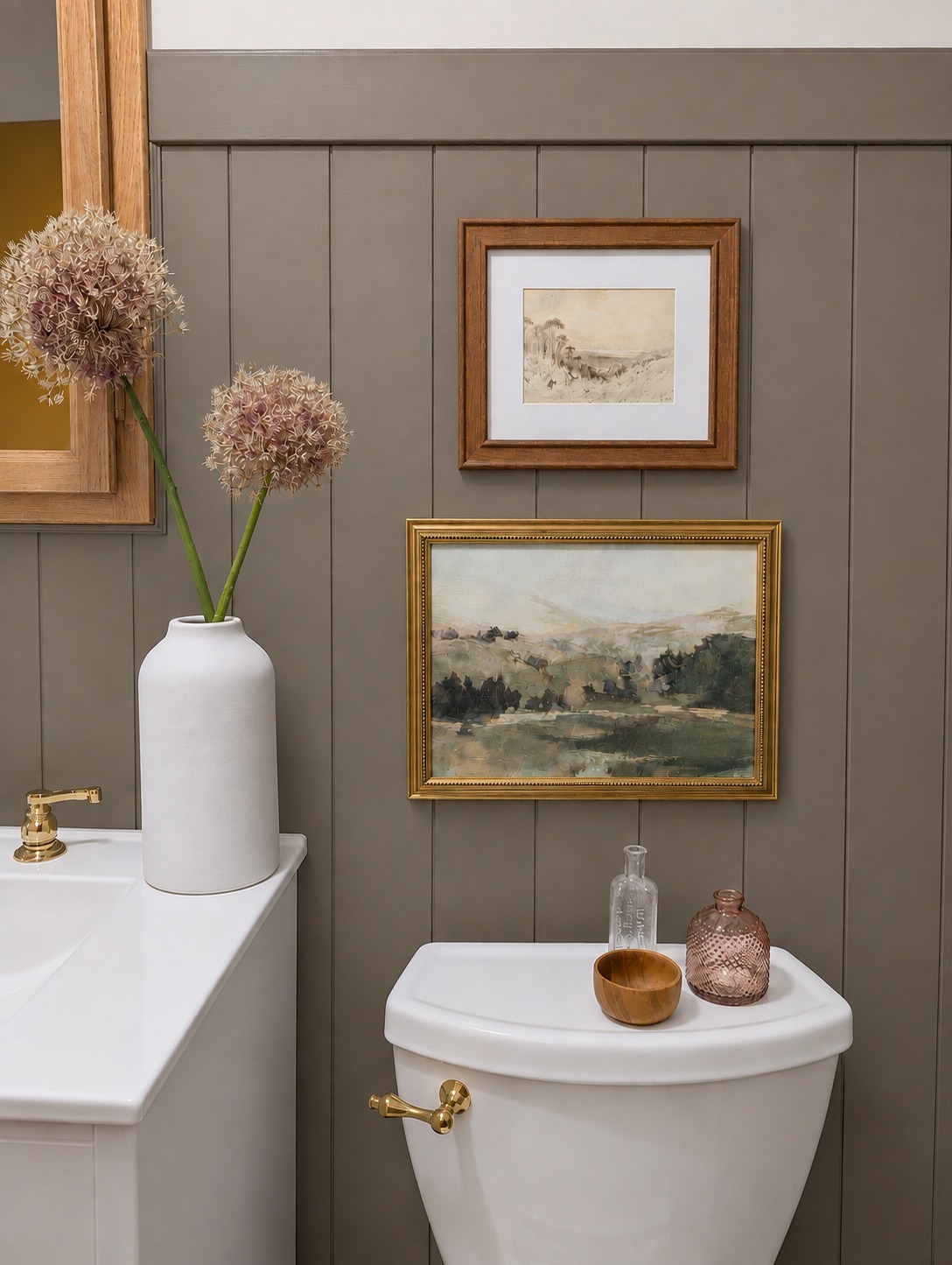 Bathroom wall vignette with framed landscape art and dried allium in a ceramic vase