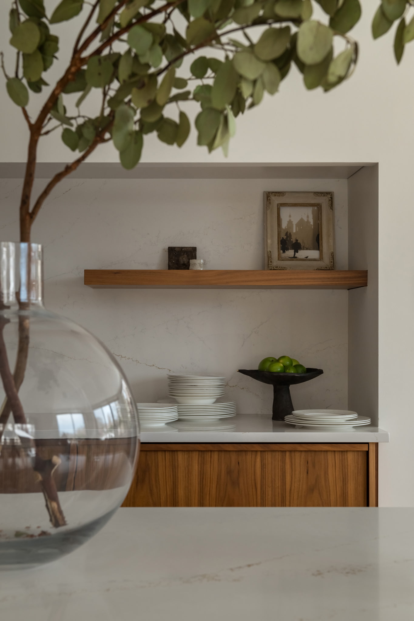 Kitchen island styled with seasonal fruit, a glass vase of branches, and pomegranates